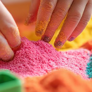 Colorful close-up of an autistic child's hands engaging with vibrant kinetic sand and sensory tools during occupational therapy, highlighting tactile stimulation and neurodiversity. space for text, --no grunge, dust, splash, --chaos 20 --ar 5:2 --v 7 Job ID: abcd343a-7867-4add-8345-59debee3883f