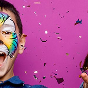 Portrait of positive cheerful little girl and boy, have fun isolated over violet color background serpentine flying.