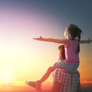 happy family at sunset. father and daughter having fun and playing in nature. the child sits on the shoulders of his father.